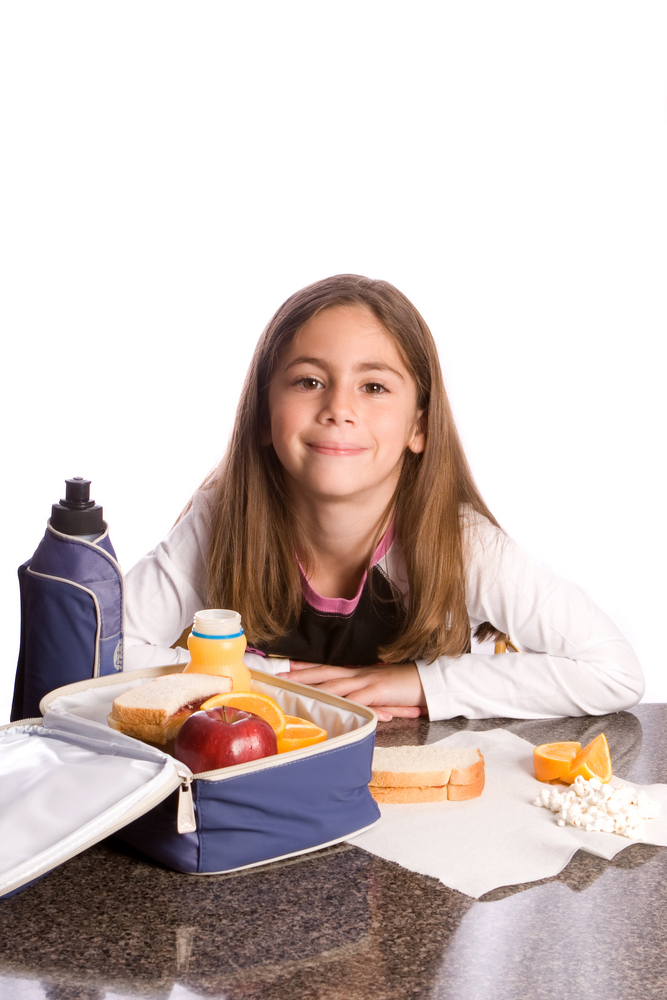 5th Grade student sitting at a lunch table with an open lunch box