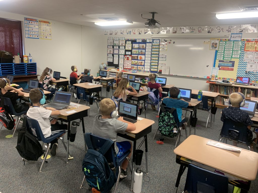 Students sitting at desks wearing wireless headphones