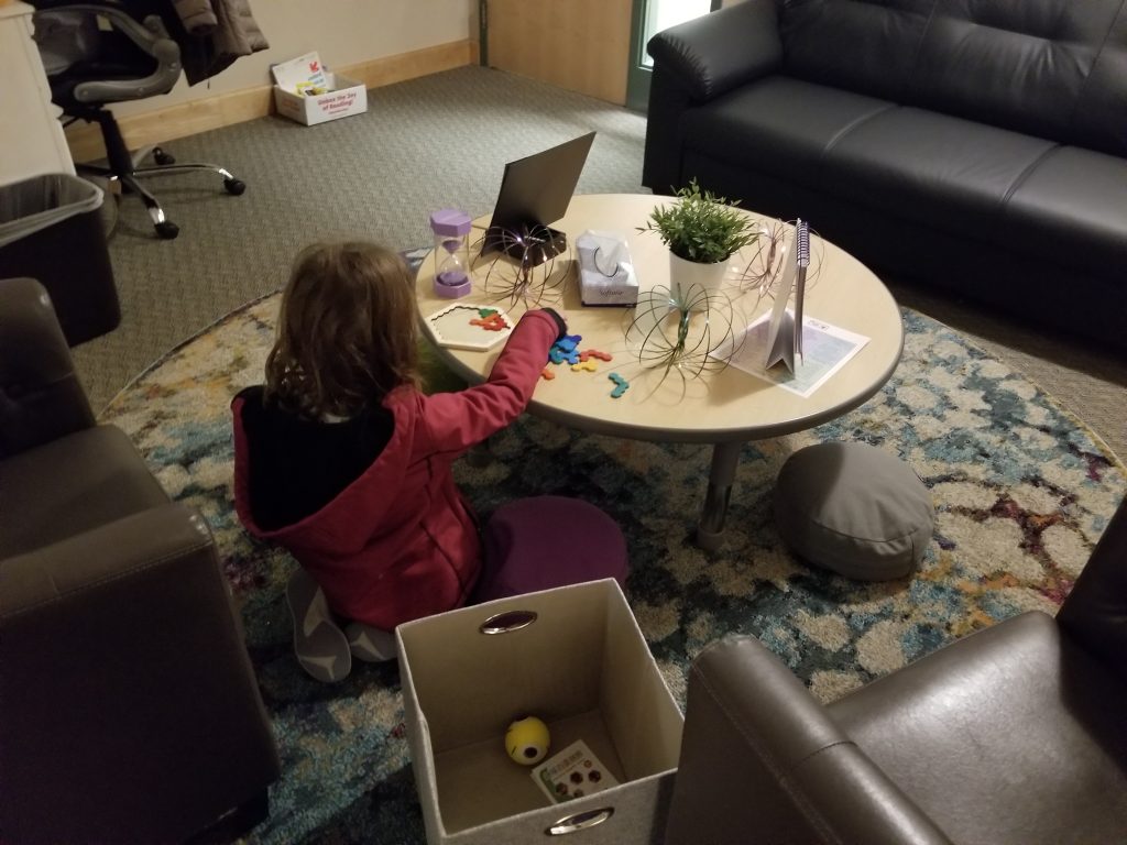 student sitting at a table working a project to self calm themself